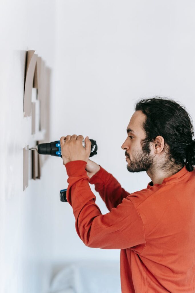 Focused man drilling into wall, enhancing home interiors with precision tools.